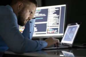 Worried,Programmer,Working,Late,At,Night,On,Multiple,Computer,Screens