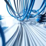 High-speed blue Ethernet cables connected to network switches in a data center, showcasing IT infrastructure and network management services.