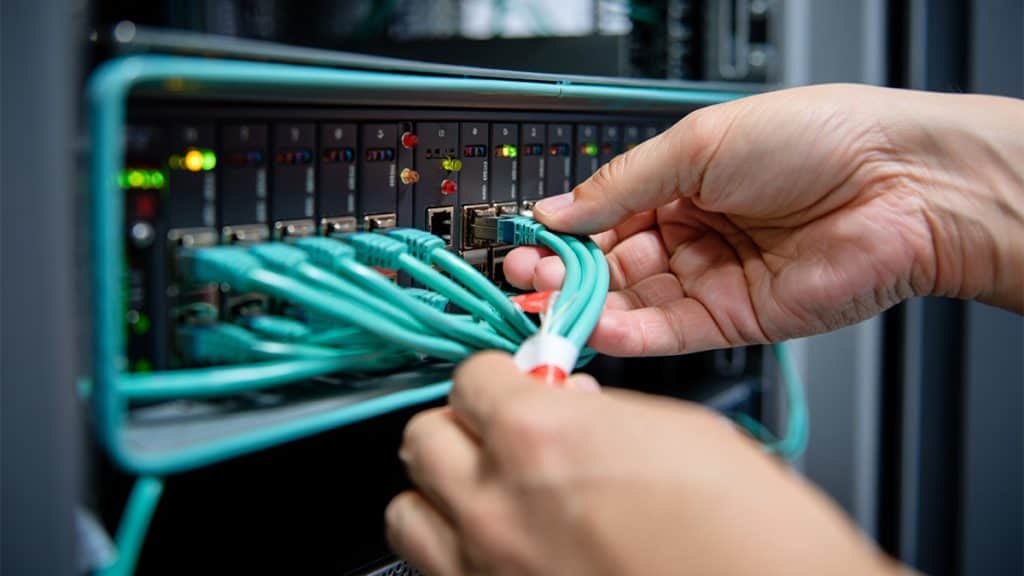High-quality image showing hands connecting Ethernet cables to a network switch in a data center, illustrating IT network setup and infrastructure.