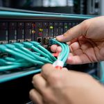 High-quality image showing hands connecting Ethernet cables to a network switch in a data center, illustrating IT network setup and infrastructure.