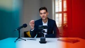 High-quality image of a professional man recording a podcast with a camera and microphone in a bright, modern office setting, representing IT and media services.