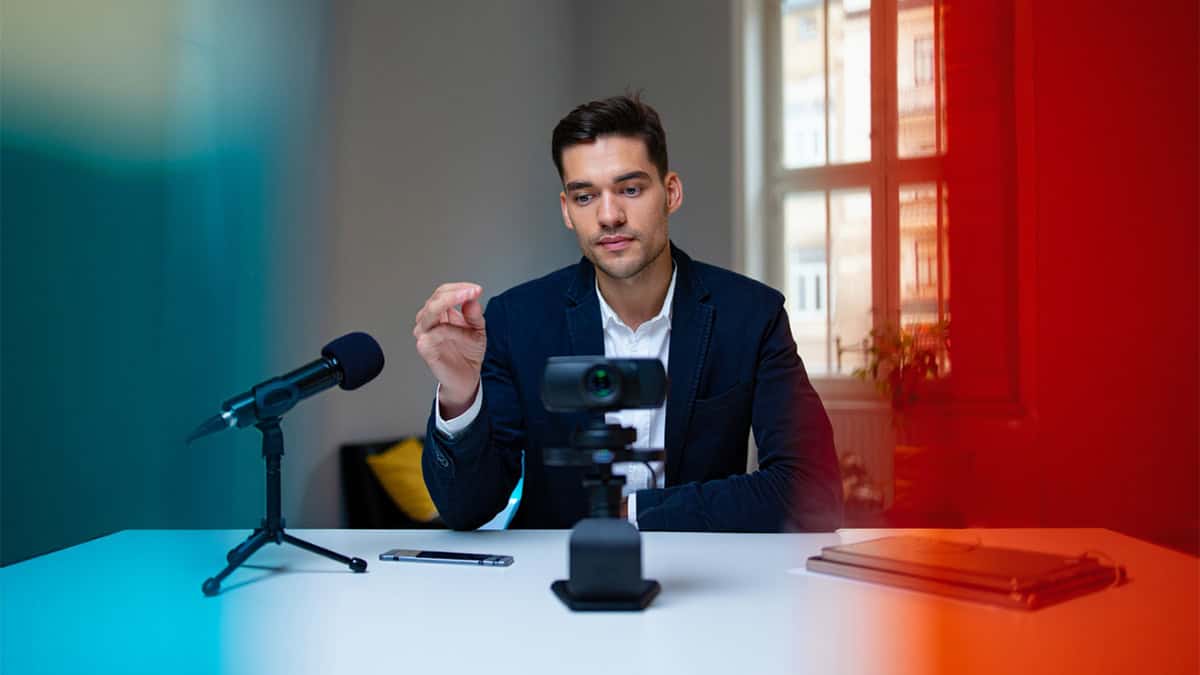 High-quality image of a professional man recording a podcast with a camera and microphone in a bright, modern office setting, representing IT and media services.