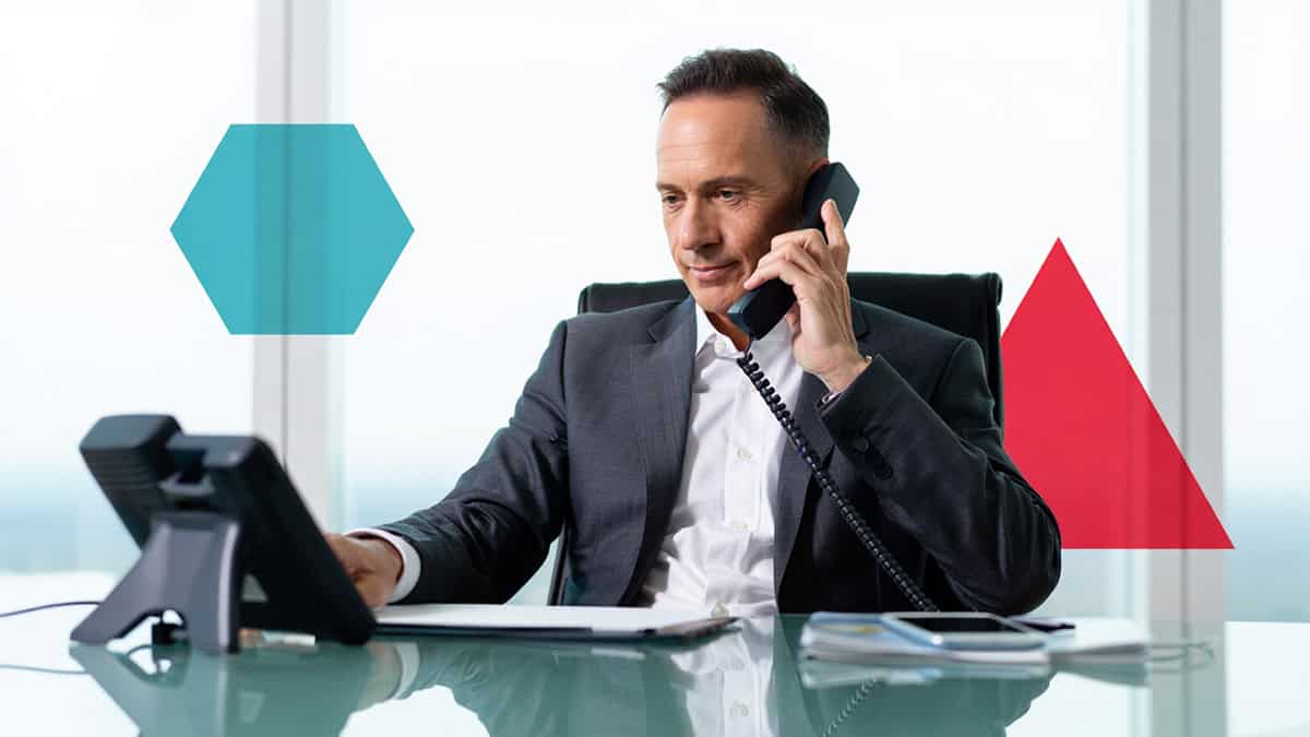 Responsive IT professional working on phone and computer at modern office for CNiC Solutions.