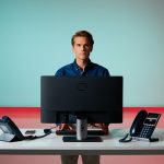 Professional IT support technician at modern office desk with computer and communication devices for CNiC Solutions.