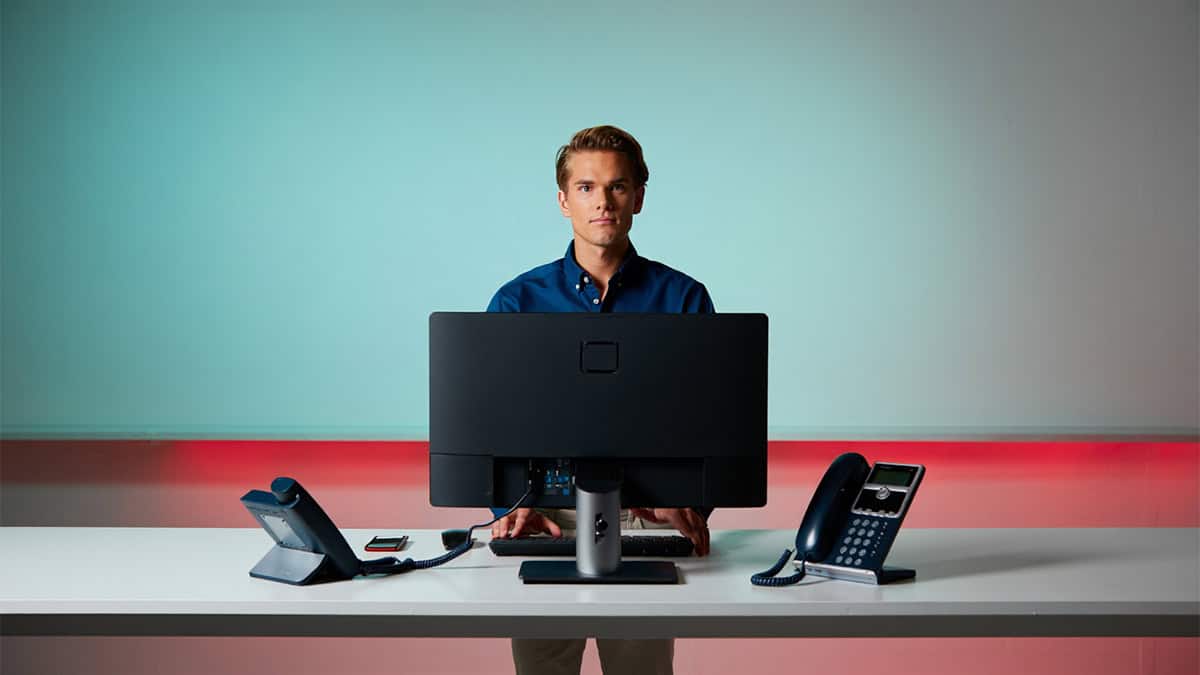 Professional IT support technician at modern office desk with computer and communication devices for CNiC Solutions.