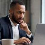 Office worker pausing before clicking a link in a suspicious email on a laptop