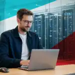 IT professional working on a laptop in a modern data center environment in Houston, TX.