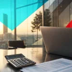 Modern office desk with laptop, budget documents, and calculator in warm light, illustrating business IT spending and budget planning